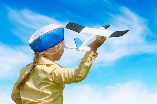 Heureux bébé fille enfant jouant avec un avion jouet sur fond de ciel d'été bleu Concept inoculant l'amour des enfants pour l'aviation