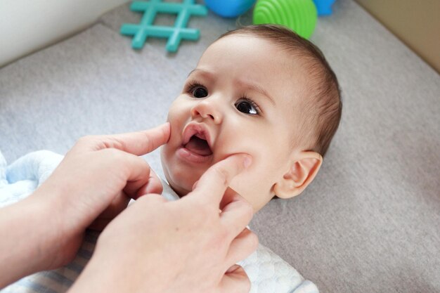 Heureux bébé garçon couché la main de la mère en appuyant sur ses joues