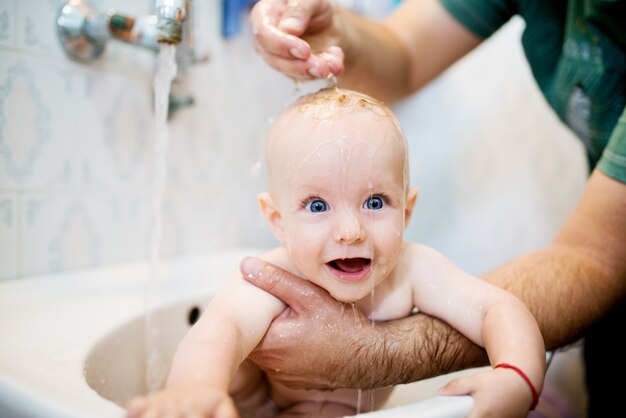 Heureux bébé riant prenant un bain. Petit enfant dans une baignoire. Enfant souriant dans la salle de bain. Lavage et baignade des nourrissons. Hygiène et soins pour les jeunes enfants.