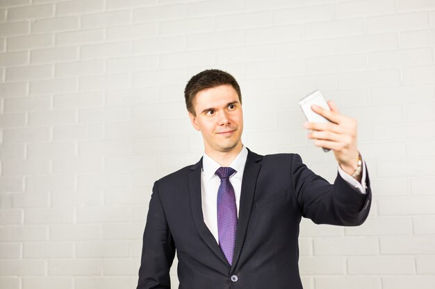 Heureux bel homme d'affaires prenant selfie au bureau