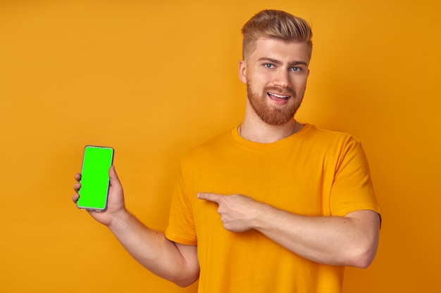 Heureux bel homme avec barbe de gingembre montre un affichage vide de smartphone avec canal alpha