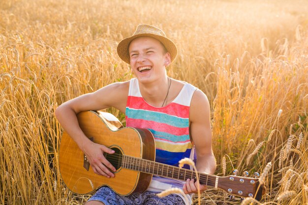 Heureux bel homme joue de la guitare sur le terrain