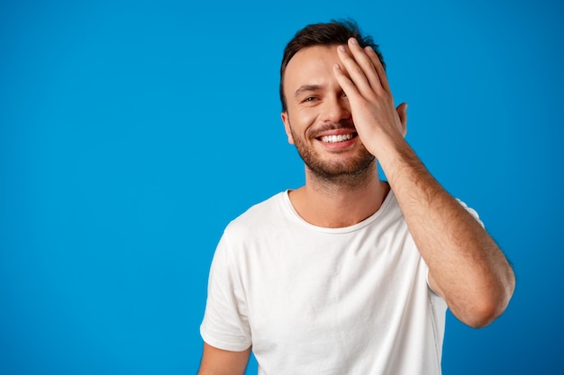 Heureux bel homme souriant sur fond bleu