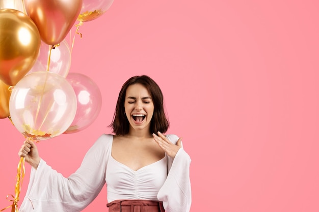 Heureux choqué émotionnel excité jeune femme européenne avec la bouche ouverte tenant de nombreux ballons gonflables