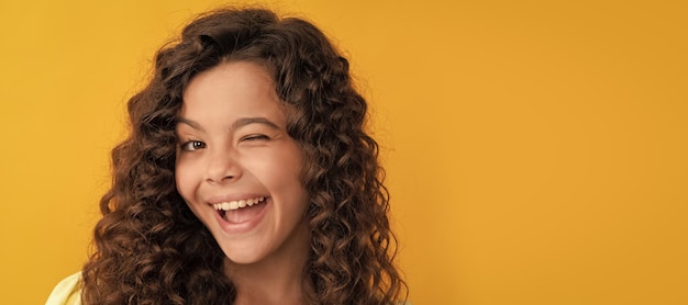 Heureux clin d'œil adolescente avec de longs cheveux bouclés et une peau parfaite crépue Visage d'enfant affiche horizontale adolescente portrait isolé bannière avec espace de copie