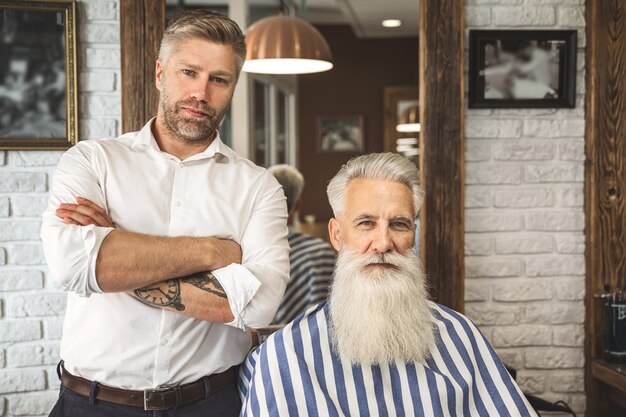 Heureux coiffeur et son client dans le salon de coiffure