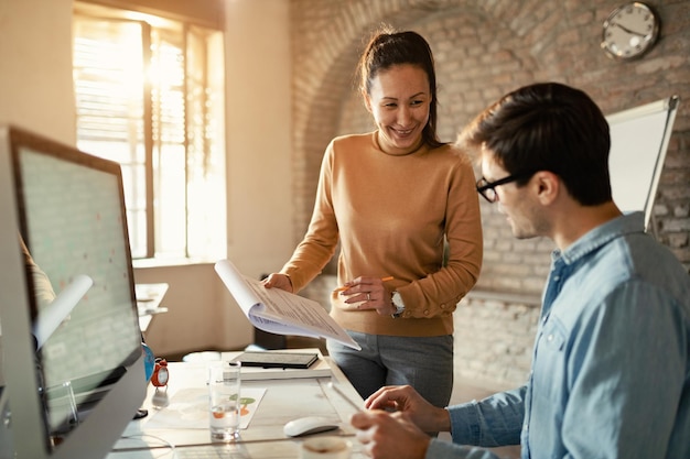 Heureux collègues d'affaires coopérant tout en analysant des rapports au bureau L'accent est mis sur la femme