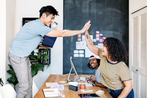 Heureux collègues divers dans une entreprise en démarrage faisant un high five