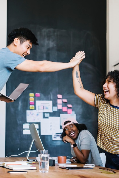 Heureux collègues diversifiés dans une entreprise en démarrage faisant un high five