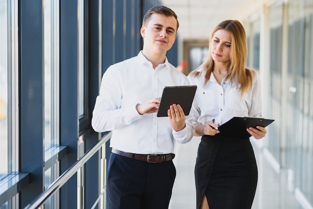 Heureux collègues de travail dans un bureau moderne à l'aide de tablette