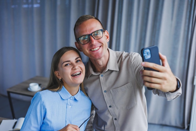 Heureux collègues de travail travaillant ensemble au bureau et utilisant le téléphone Des collègues prennent un selfie pendant une pause