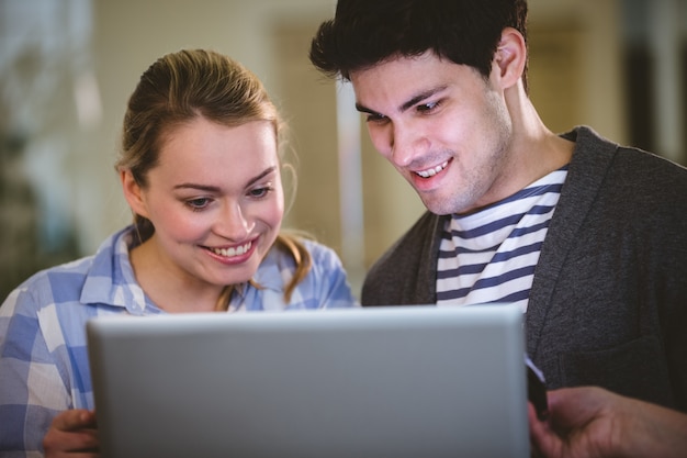 Heureux collègues utilisant un ordinateur portable au bureau créatif