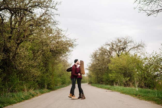 Heureux couple actif marchant et s'amusant sur la route de campagne