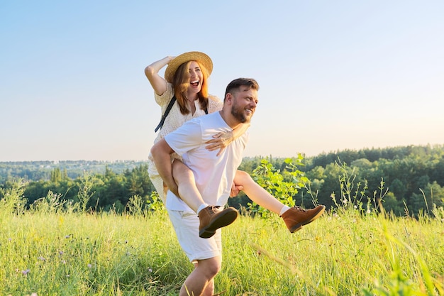 Heureux couple adulte riant s'amusant à l'extérieur fond de ciel nature