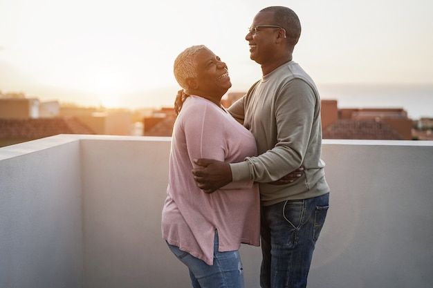 Heureux couple africain dansant à l'extérieur au coucher du soleil - Flou artistique sur le visage de l'homme