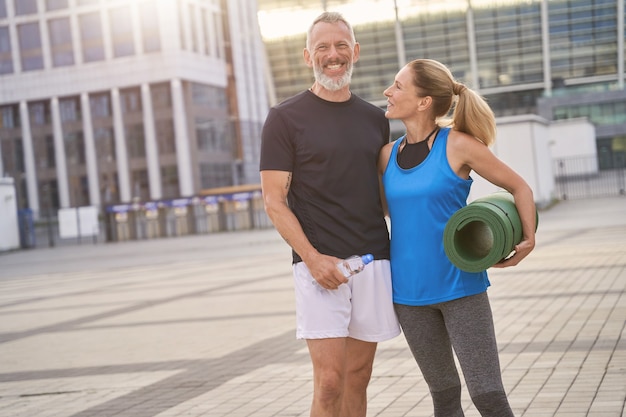 Heureux couple d'âge mûr homme et femme en tenue de sport posant ensemble après l'entraînement du matin