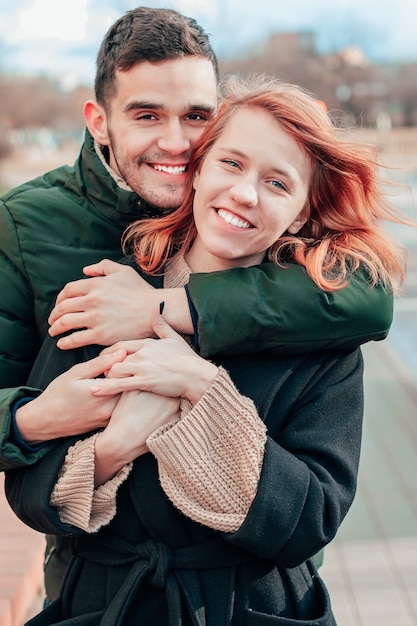 Heureux couple aimant souriant et étreignant dans la rue. Histoire d'amour de deux personnes heureuses - Portrait moyen