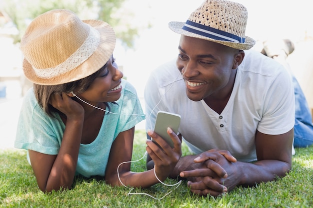 Heureux couple allongé dans le jardin ensemble en écoutant de la musique