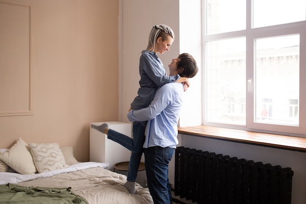 Heureux couple amoureux étreignant dans la chambre et concept de baisers, d'amour et de relations.