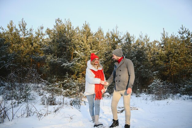 Heureux couple d'amoureux marchant dans la forêt d'hiver enneigée passant des vacances de Noël ensemble Activités saisonnières en plein air Capture de style de vie