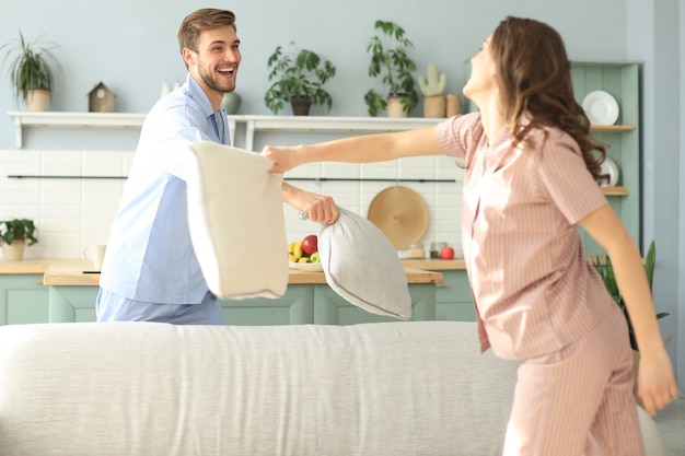 Heureux couple d'amoureux s'amusant tout en faisant une bataille d'oreillers dans le salon.