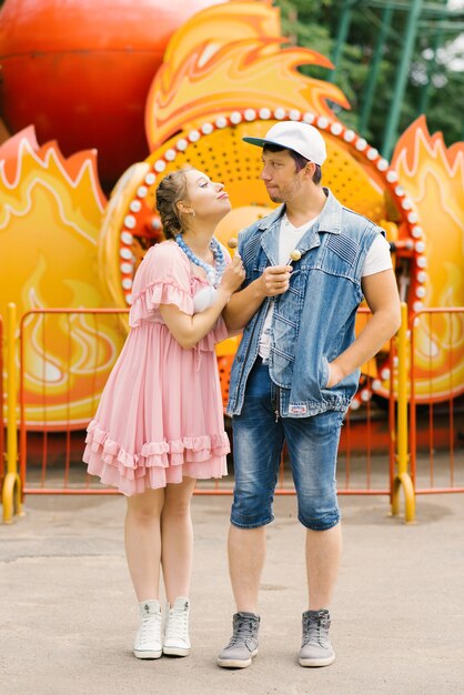 Heureux couple amoureux s'amuser dans un parc d'attractions, manger des sucettes