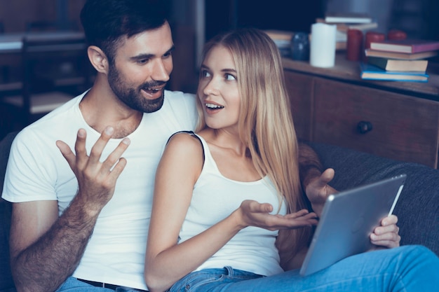 Heureux couple amoureux surfant sur tablette à la maison.