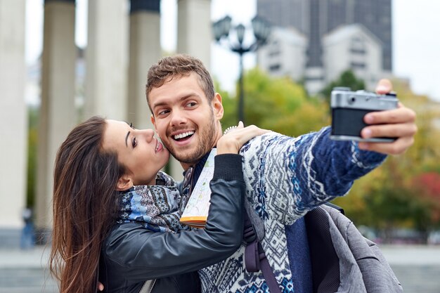 Heureux couple amoureux de touristes prenant selfie sur appareil photo rétro dans la ville urbaine. Femme embrassant un homme sur une photo