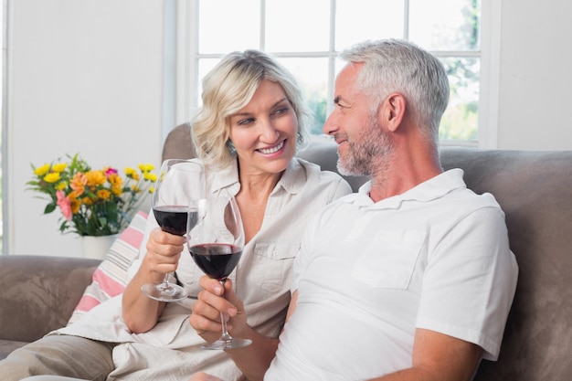 Heureux couple d&#39;amoureux avec verres à vin dans le salon