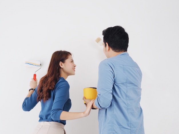 Heureux couple asiatique amoureux peinture mur à la nouvelle maison ensemble