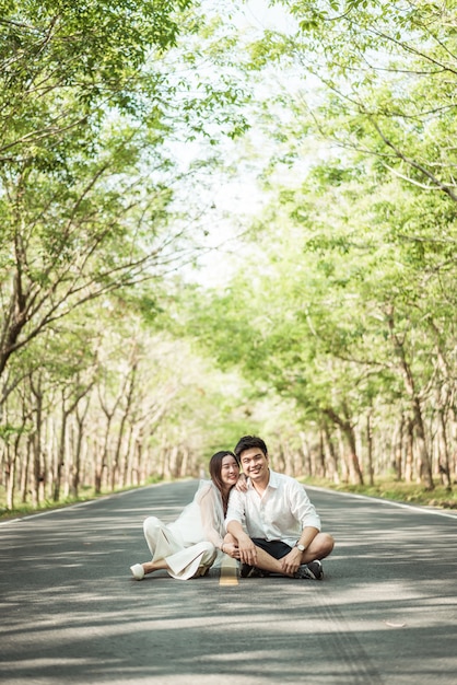 Heureux couple asiatique amoureux sur route avec arche d'arbre