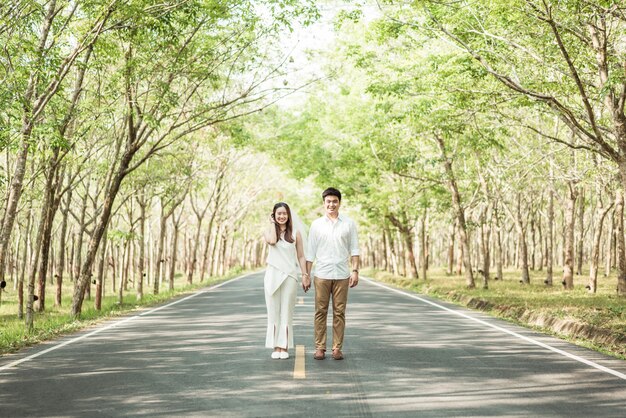 Heureux couple asiatique amoureux sur route avec arche d'arbre