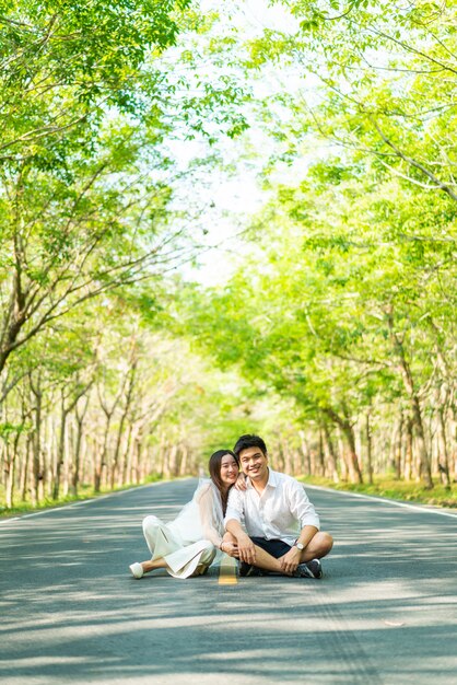 Heureux couple asiatique amoureux sur route avec arche d'arbre