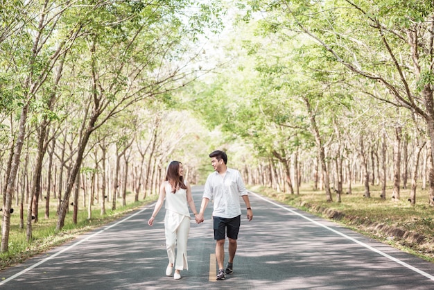 Heureux couple asiatique amoureux sur route avec arche d'arbre