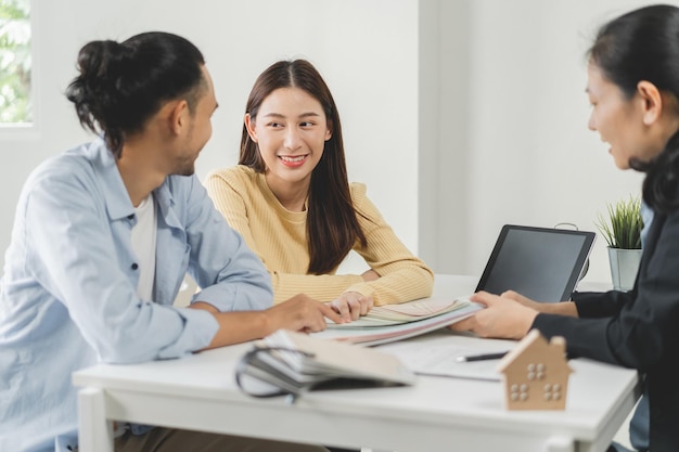 Heureux couple asiatique client gens choisissent la couleur sur le tableau de la palette pour la peinture swatch sur le mur pour la nouvelle maison avec une femme designer au bureau