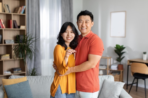 Heureux couple asiatique montrant la clé de leur nouvel appartement