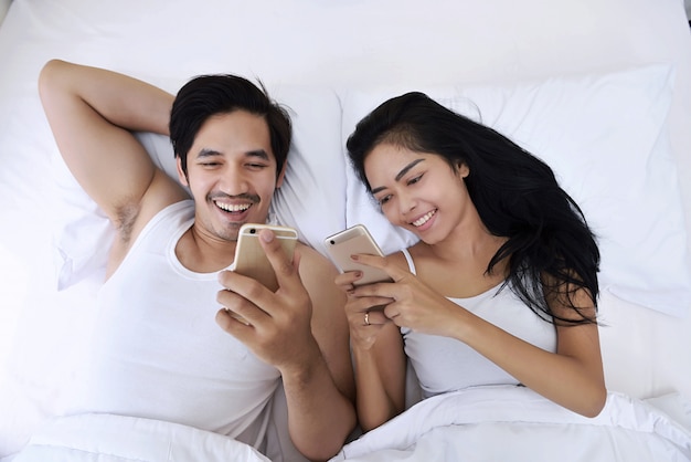 Heureux couple asiatique avec les smartphones