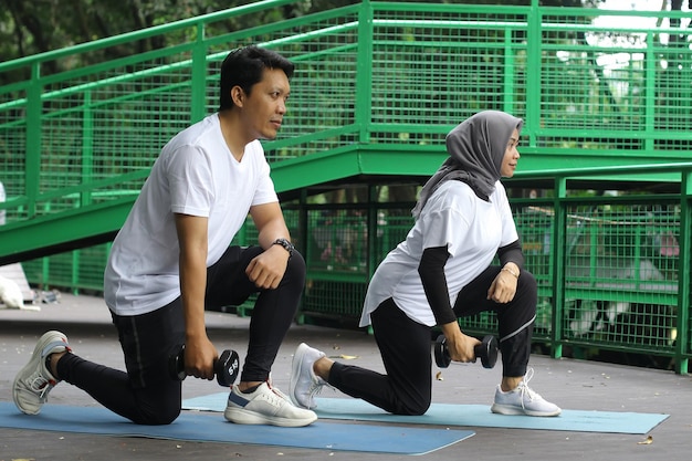 Heureux couple asiatique travaillant avec des haltères en plein air. Concept de santé et de remise en forme.