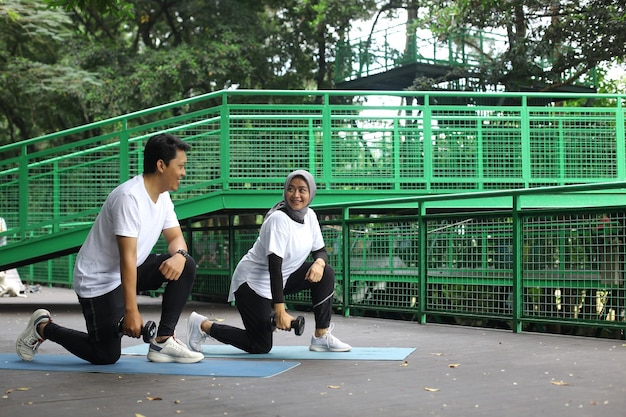 Heureux couple asiatique travaillant avec des haltères en plein air. Concept de santé et de remise en forme.