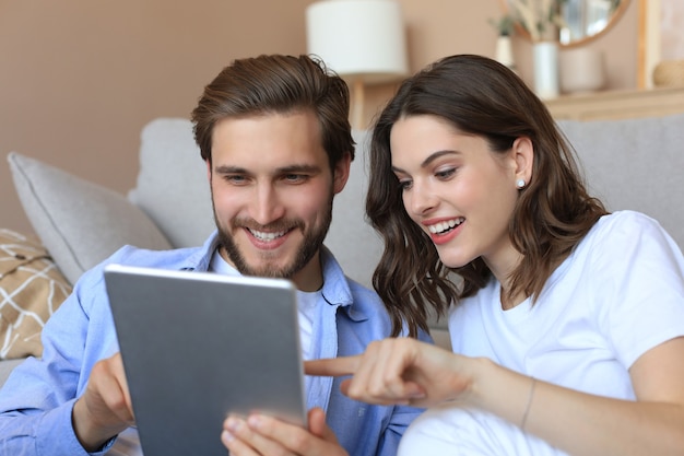 Heureux couple assis et planifiant une nouvelle décoration à la maison avec une tablette, rénovation et design d'intérieur pour la nouvelle maison.