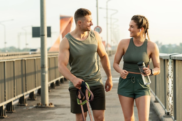 Heureux couple athlétique après une séance d'entraînement physique marchant dans une rue pendant l'heure du coucher du soleil