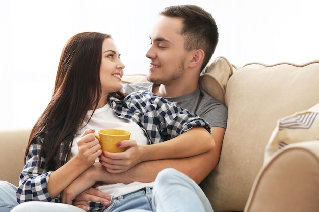 Heureux couple avec une boisson chaude sur le canapé