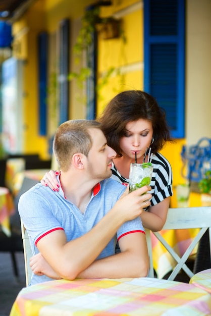 Photo heureux couple buvant de la limonade dans un café extérieur.