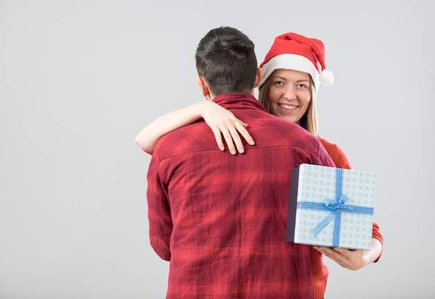 Heureux couple avec cadeau de Noël isolé sur fond gris