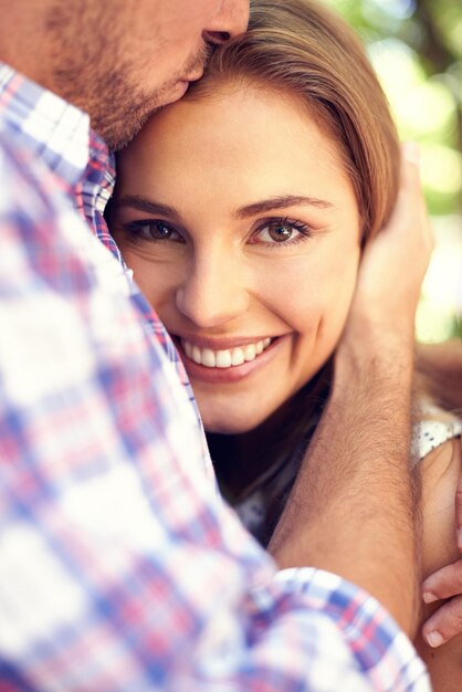 Photo heureux couple câlin femme et portrait dans le parc agrandi le jour de la saint-valentin amour et romance avec sourire homme baiser et étreinte en plein air pour sortir ensemble aventure romantique et créer des liens avec soin au soleil