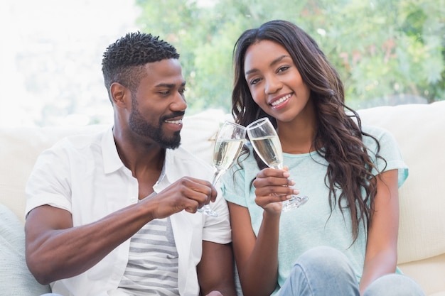 Heureux couple sur le canapé ayant du champagne