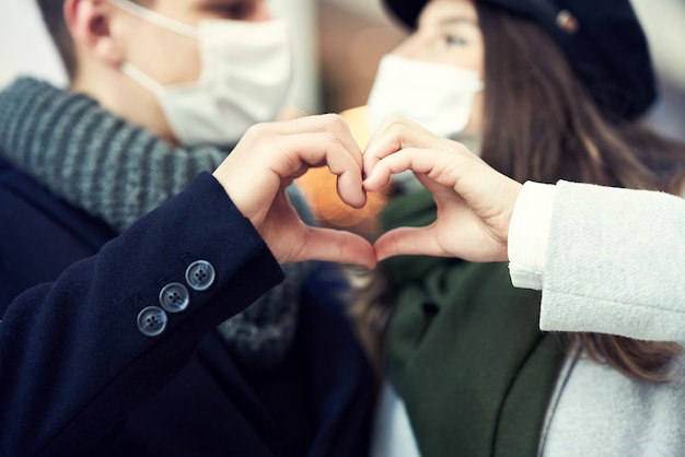 Heureux couple célébrant la Saint-Valentin dans des masques pendant la pandémie de covid-19 dans la ville