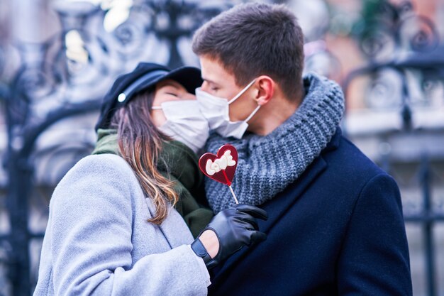 Heureux couple célébrant la Saint-Valentin dans des masques pendant la pandémie de covid-19 dans la ville