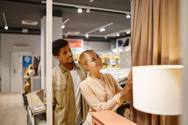 Heureux couple choisissant des rideaux faisant des achats en magasin