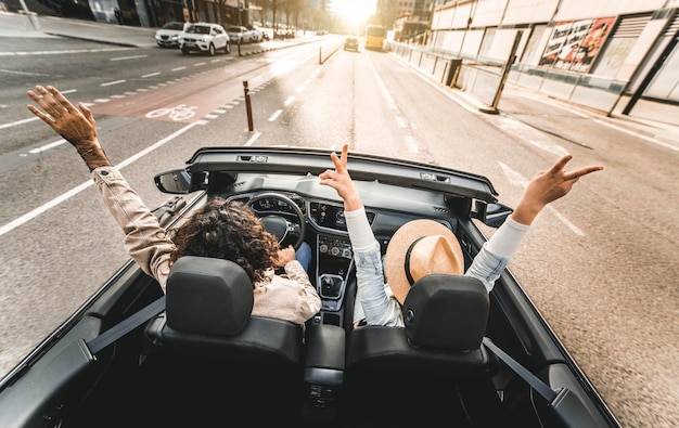 Heureux couple conduisant sur la rue de la ville en voiture décapotable